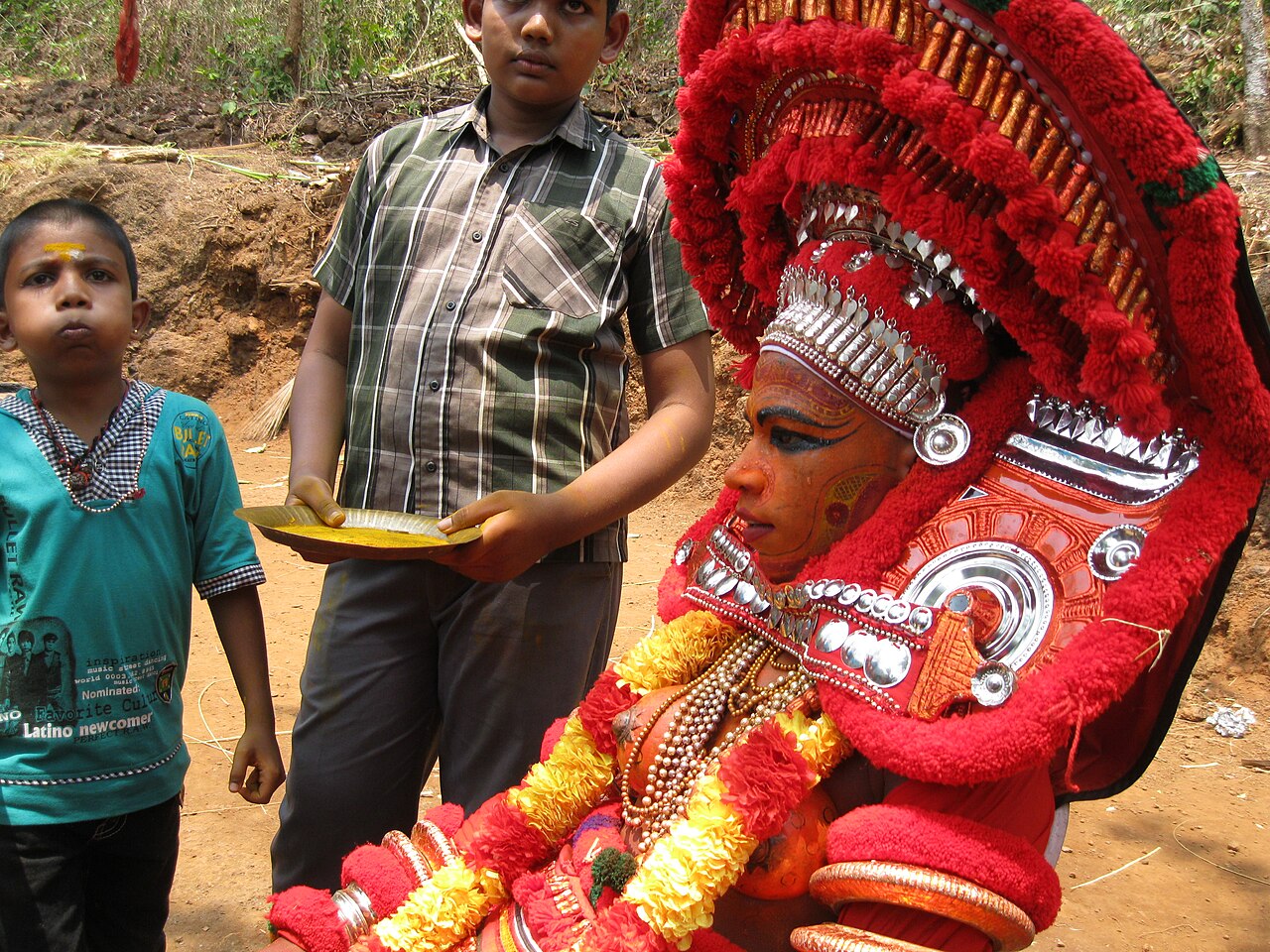 Τελεστής του Τέγιαμ [Theyyam] ενσαρκώνει την Κουράτι, μία από τις θεότητες του είδους, στο Μπλάθουρ της βόρειας Κεράλα (2012). Στο τελετουργικό αυτό είδος ο τελεστής, που ανήκει παραδοσιακά σε κάστες χαμηλής κοινωνικής θέσης, γίνεται για όσο διαρκεί η επιτέλεση η ίδια η θεότητα και δέχεται τη λατρεία όλης της κοινότητας. Το Τέγιαμ θέτει στην εθνοθεατρολογία το ερώτημα πού τελειώνει η τελετουργία και πού αρχίζει το θέαμα.