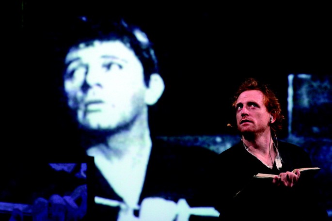 Σκηνή από τον Hamlet [Άμλετ] (2006) της Wooster Group [Γούστερ Γκρουπ] σε σκηνοθεσία της Elizabeth LeCompte [Ελίζαμπεθ ΛεΚοντ]. Η αναδιαδραμάτιση μιμείται την παράσταση του John Gielgud [Τζων Γκήλγκουντ] με τον Richard Burton [Ρίτσαρντ Μπάρτον] (Μπρόντγουεϊ, 1964). Η κινηματογραφημένη καταγραφή εκείνης της παράστασης προβάλλεται επί σκηνής. Φωτογραφία: Paula Court.