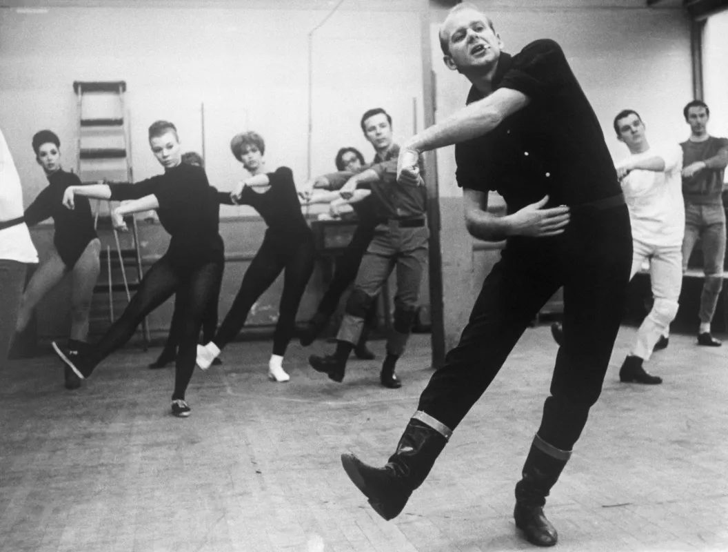 Ο Bob Fosse [Μπομπ Φόσσι] καθοδηγεί μέλη του θιάσου στις δοκιμές του μιούζικαλ Pleasures and Palaces [Απολαύσεις και παλάτια, 1965]. Η εικόνα αναδεικνύει τη σωματική μετάδοση του κινητικού περιεχομένου από τον χορογράφο στους ερμηνευτές και στις ερμηνεύτριες, διαδικασία κεντρική στη διαμόρφωση του αναγνωρίσιμου ύφους του Fosse.