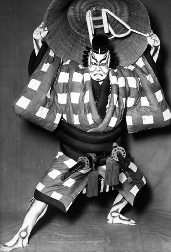 [[#Ονόε Κικουγκορό ΣΤ΄ [Onoe Kikugorō VI]#]] (1885-1949) στον ρόλο του Ουμεόμαρου [Umeōmaru] στο έργο Καμπούκι Σουγκαουάρα Ντέντζου Τεναράι Καγκάμι [Sugawara Denju Tenarai Kagami, 菅原伝授手習鑑] (α΄ παράσταση: 1746). Στο καμπούκι, ο μονόλογος λαμβάνει τη μορφή του τσουράνε (tsurane): εκτεταμένης ρητορικής απαγγελίας, κατά την οποία ο ηθοποιός ακινητοποιείται σε τυποποιημένη στάση (μιέ/mie) και εκφωνεί τον λόγο του με υψηλά στυλιζαρισμένη φωνητική τεχνική, αναδεικνύοντας μια παράδοση μονολόγου ριζικά διαφορετική από τη δυτική. 