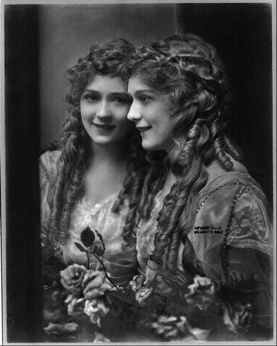 Mary Pickford (1892-1979), φωτογραφικό πορτραίτο με κατοπτρικό είδωλο, 10 Νοεμβρίου 1914, copyright [[#William S. Earle [Ουίλλιαμ Σ. Ερλ]#]] (Library of Congress, Prints and Photographs Division, Washington D.C.). Η Καναδοαμερικανίδα ηθοποιός, γνωστή ως «America's Sweetheart» [«η αγαπημένη της Αμερικής»] και συνιδρύτρια της εταιρείας United Artists, υπήρξε η κατεξοχήν ενσάρκωση της ενζενύ στον πρώιμο κινηματογράφο του βωβού, με τους χαρακτηριστικούς της ρόλους αθώων, ζωηρών και συναισθηματικών νεανίδων (συχνά με τους γνωστούς της βοστρύχους) να καθορίζουν την αμερικανική εικόνα της κινηματογραφικής νεότητας στη δεκαετία του 1910 και του 1920.