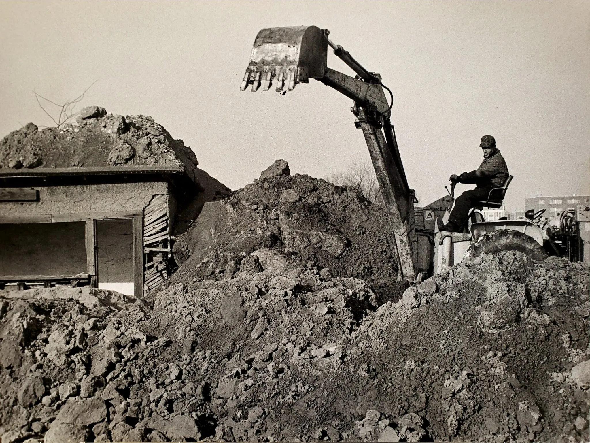 Robert Smithson, Partially Buried Woodshed [Μισοθαμμένη ξύλινη καλύβα], 1970, Kent State University, ΗΠΑ.Τον Ιανουάριο του 1970, ο Smithson ζήτησε από τον χειριστή ενός εκσκαφέα να αποθέσει χώμα πάνω σε μια εγκαταλελειμμένη ξύλινη καλύβα που είχε εντοπίσει στους χώρους της πανεπιστημιούπολης του Kent State University, έως ότου το βάρος του χώματος προκαλέσει τη σταδιακή υποχώρηση της στέγης. Η διαδικασία αυτή, κατά την οποία η κατασκευή οδηγείται σε μερική κατάρρευση, συνδέεται με την έννοια της εντροπίας, κεντρική στη σκέψη και το έργο του Smithson.Λίγους μήνες αργότερα, στις 4 Μαΐου 1970, τέσσερις φοιτητές που συμμετείχαν σε διαδήλωση κατά του πολέμου του Βιετνάμ σκοτώθηκαν από την Εθνοφρουρά του Οχάιο στην ίδια πανεπιστημιούπολη. Η ημερομηνία «May 4, 1970» γράφτηκε στους τοίχους της καλύβας χωρίς την έγκριση του Smithson, συνδέοντας εκ των υστέρων το έργο με το συγκεκριμένο ιστορικό γεγονός. Η καλύβα, η οποία καταστράφηκε σταδιακά και εξαφανίστηκε πλήρως έως το 1984, έχει έκτοτε ερμηνευθεί ως εικόνα φθοράς, κατάρρευσης και πολιτικής και κοινωνικής αποσταθεροποίησης, ενώ η σχέση της με τα γεγονότα του Kent State έχει προσδώσει στο έργο ιδιαίτερη ιστορική και πολιτική διάσταση.
