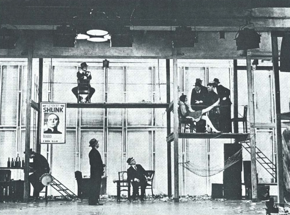 Το θεατρικό του Brecht Στη ζούγκλα των πόλεων [Im dickicht der städte/In the jungle of cities, 1923], που πρωτοπαίχτηκε στο Residenztheater [Θέατρο Ρεζιντέντς] του Μονάχου, παρουσιάζει τον καπιταλισμό ως μια ανελέητη «ζούγκλα», όπου οι ανθρώπινες σχέσεις μετατρέπονται σε πεδίο πάλης για εξουσία. Στην φωτογραφία απεικονίζεται το σκηνικό του έργου, από την παράσταση του 1968, που ανέβηκε στην πειραματική σκηνή του Kammerspiele [Κάμμερσπίλε] του Μονάχου, σε σκηνοθεσία του Peter Stein, με κεντρικό χώρο το μπαρ «Πικαντίλλυ» ["Piccadilly"], που συμβολίζει την παρακμή, την εκμετάλλευση και την αλλοτρίωση του ανθρώπου μέσα στον καπιταλιστικό κόσμο. &nbsp;