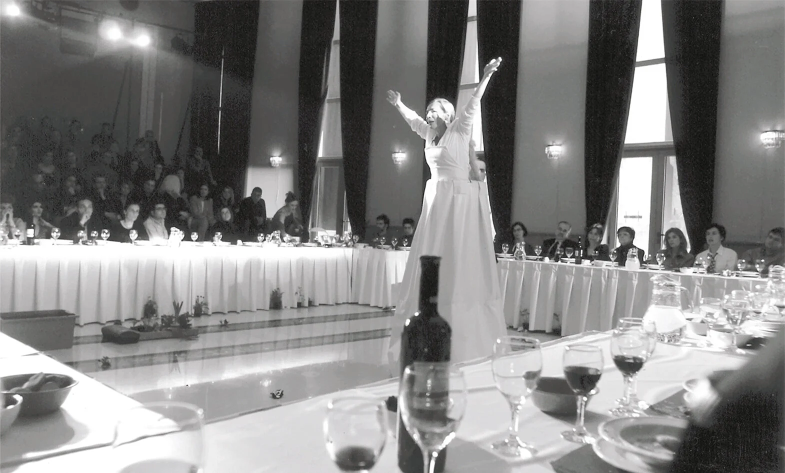 Μιχαήλ Μαρμαρινός, Εθνικός Ύμνος (2001), θέατρο «Διπλούς Έρως», σε συμπαραγωγή με το ΔΗΠΕΘΕ Κέρκυρας. Οι θεατές κάθονται σε τραπέζι σχήματος Π και μοιράζονται ένα γεύμα που μαγειρεύεται επί τόπου. Ο λόγος της παράστασης συντίθεται από κείμενα 33 Ελλήνων και ξένων συγγραφέων. Η παράθεση ετερόκλητων κειμένων και η κατάλυση του ορίου ανάμεσα σε σκηνή και πλατεία απηχούν τον μεταμοντερνισμό.